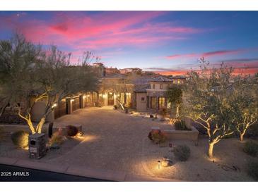 Beautiful home at twilight with a brick driveway, desert landscaping, and exterior lighting at 15956 E Tombstone Trl, Fountain Hills, AZ 85268