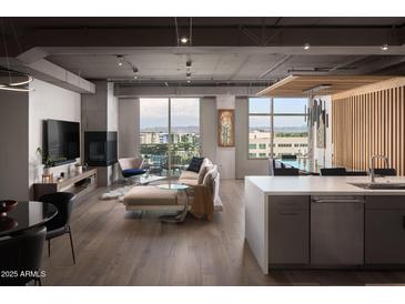 Modern living room with hardwood floors, fireplace, and city views from expansive windows at 2211 E Camelback Rd # 605, Phoenix, AZ 85016