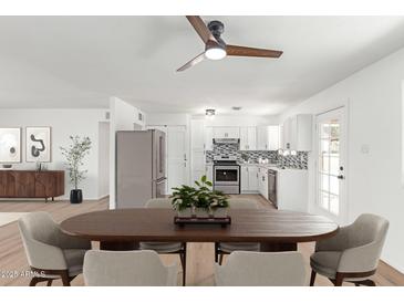 Bright kitchen boasts stainless steel appliances, white cabinets, and stylish backsplash, complemented by a cozy dining area at 5939 W Cheery Lynn Rd, Phoenix, AZ 85033