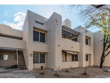 Tan two-story condo with a wooden staircase and rock landscaping under a blue sky at 11333 N 92Nd St # 2080, Scottsdale, AZ 85260