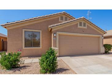 Tan single-story home with a two-car garage and desert landscaping on a bright, sunny day at 16508 N 114Th Dr, Surprise, AZ 85378