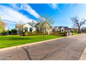 Beautiful exterior view of a single-Gathering home with a large lawn, mature landscaping, and brick driveway at 20690 E Sunset Dr, Queen Creek, AZ 85142
