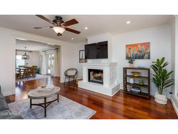 Cozy living room featuring a fireplace, modern decor, hardwood floors, and open access to the dining area at 3514 N 83Rd St, Scottsdale, AZ 85251