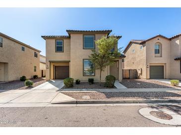 Tan two-story home with a two-car garage and simple desert landscaping at 5233 W Albeniz Pl, Phoenix, AZ 85043