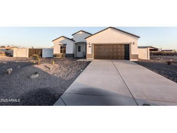 Inviting single-Gathering home featuring a xeriscaped yard and a long concrete driveway leading to the attached garage at 8315 W Concordia Dr, Arizona City, AZ 85123