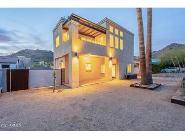 Modern two-story home showcasing a balcony, tall windows, desert landscaping, and stylish architectural lighting at 9834 N 1St St, Phoenix, AZ 85020