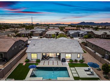 Aerial view of a backyard pool with lounge chairs, turf, and desert landscaping under a vibrant sunset sky at 22372 E Duncan St, Queen Creek, AZ 85142