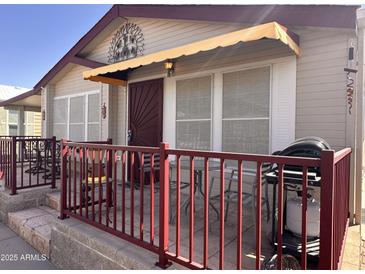 Inviting front porch with a red metal railing, a neutral tan exterior, and awning over the front door at 650 N Hawes Rd # 4609, Mesa, AZ 85207