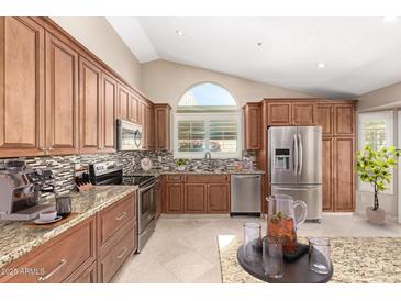 Well-lit kitchen featuring granite countertops, stainless steel appliances, and custom cabinetry at 8804 E Sunnyside Dr, Scottsdale, AZ 85260
