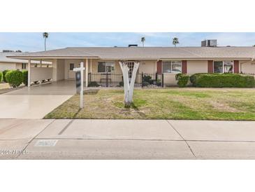 Charming single story home featuring a well-manicured lawn and a covered carport at 10815 W Hatcher Rd, Sun City, AZ 85351