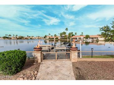 A lake view with a boat, landscaping, and a patio leading to the water at 11101 W Sieno Pl, Avondale, AZ 85392