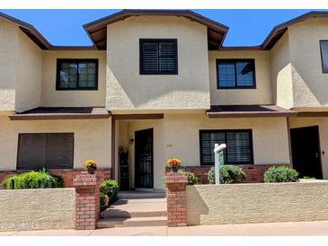 Inviting exterior showcasing a townhouse with a well-manicured lawn and brick accents at 170 E Guadalupe Rd # 154, Gilbert, AZ 85234