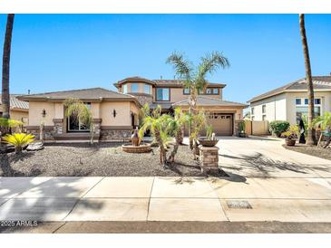 Beautiful two-story home featuring a well-manicured yard with mature palm trees and a circular driveway at 3925 E Vallejo Dr, Gilbert, AZ 85298