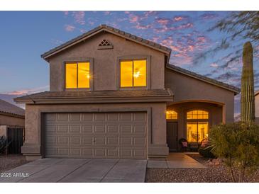 Charming two-story home featuring a two-car garage and desert landscaping at dusk at 10468 E Raintree Dr, Scottsdale, AZ 85255