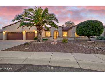 Inviting single-story home with well-maintained landscaping, desert accents, and a charming entryway with a beautiful palm tree at 16927 W Desert Blossom Way, Surprise, AZ 85387