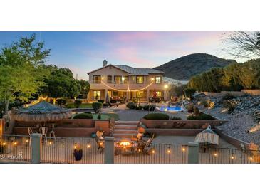 Expansive backyard with pool, fire pit, lush greenery, and mountain views at dusk at 1922 E Saltsage Dr, Phoenix, AZ 85048