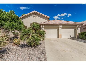 Beige home with tile roof and desert landscaping, including small palm trees, gravel, and a two-car garage at 2535 N Pinnule Cir, Mesa, AZ 85215