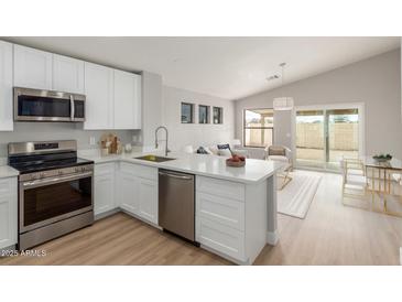Bright kitchen with white cabinets, stainless steel appliances, and an open concept to the living and dining areas at 8541 N 112Th Ave, Peoria, AZ 85345