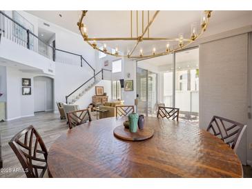 Dining area showcasing a large wood table and a stylish chandelier, with views of the spacious living room at 9390 N 115Th St, Scottsdale, AZ 85259