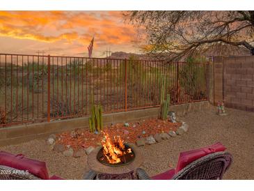 Inviting backyard with fire pit, seating area, desert landscaping, and mountain views at sunset at 10356 E Meandering Trail Ln, Gold Canyon, AZ 85118