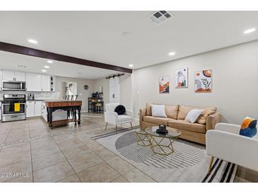 Spacious living room featuring modern décor, comfortable seating, and an open layout with a view into the kitchen at 13614 N 38Th Pl, Phoenix, AZ 85032