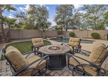 Inviting backyard featuring a pool with a waterfall and fire pit seating area, perfect for entertaining at 45583 W Sheridan W Rd, Maricopa, AZ 85139