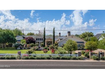 Charming home with a lush front yard, white picket fence, and vibrant rose bushes at 5431 E Lafayette Blvd, Phoenix, AZ 85018
