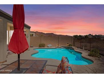 Relaxing pool area with lounge chairs, a red umbrella, and desert views in the backyard at 8377 S Mountain Air Ln, Gold Canyon, AZ 85118