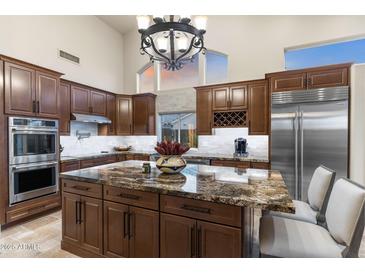 This kitchen features a large island, stainless steel appliances and custom cabinets at 11053 E Hedgehog Pl, Scottsdale, AZ 85262