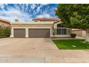 Two-car garage with a neutral color scheme, complemented by lush landscaping and a well-maintained lawn at 1210 E Azure Sea Ln, Gilbert, AZ 85234