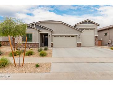 Charming single-story home featuring a three car garage, desert landscaping, and a stone facade at 18988 W Cortez St, Surprise, AZ 85388