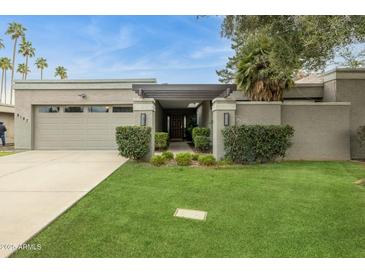 Charming single-story home featuring a well-manicured lawn and a two car garage at 8187 E Del Caverna Dr, Scottsdale, AZ 85258