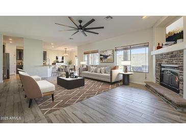 Open-concept living space with fireplace, hardwood flooring, and large windows offering natural light at 16462 W Rowel Rd, Surprise, AZ 85387