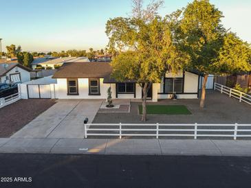 Charming single-story home with well-manicured landscaping, mature trees, and a white picket fence at 7316 W Carol Ave, Peoria, AZ 85345