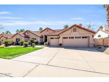 Charming single-story home with a well-manicured lawn, mature trees, and a spacious three-car garage at 8935 E Larkspur Dr, Scottsdale, AZ 85260
