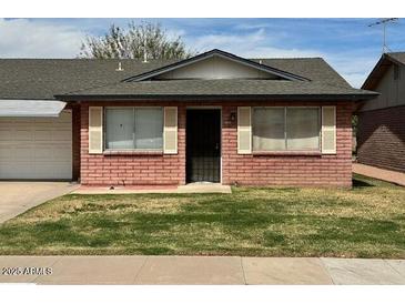 Charming single-story home features a brick facade, well-maintained lawn, and a cozy front entrance at 9638 W Cinnabar Ave # B, Peoria, AZ 85345
