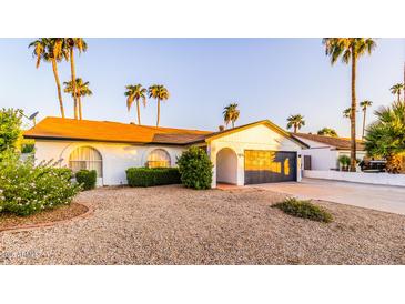 Charming single-story home featuring a desert landscape, palm trees, and a two-car garage at 10640 E Mercer Ln, Scottsdale, AZ 85259