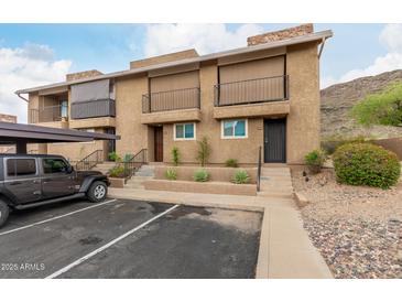 Inviting exterior view of townhome featuring a carport, desert landscaping and private balconies with iron railings at 1545 E Sahuaro Dr # 12, Phoenix, AZ 85020