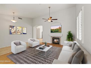 Bright living room featuring a fireplace, ceiling fan, vaulted ceilings, and contemporary decor at 16155 E Glenview Pl, Fountain Hills, AZ 85268