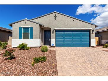 Charming single-story home featuring a blue garage door and decorative stone landscaping at 17454 W Red Fox Rd, Surprise, AZ 85387