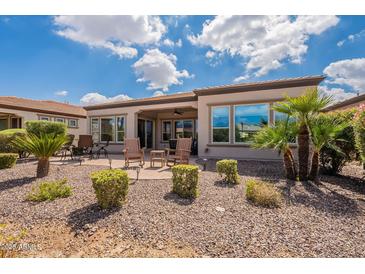 Landscaped backyard includes stone ground cover, lounge seating, and manicured shrubbery at 37036 N Stoneware Dr, Queen Creek, AZ 85140