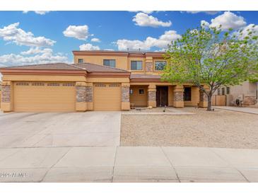 Inviting two-story tan home with a three-car garage and stone accents in a well-kept neighborhood at 4419 W Lodge Dr, Laveen, AZ 85339