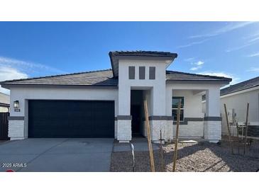 Contemporary home featuring a gray roof, neutral stucco, decorative stone accents, and a two-car garage at 25442 W Graham Trl, Buckeye, AZ 85326