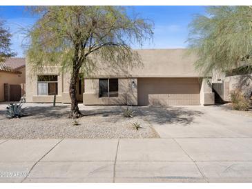 Beige single-story home with a well-maintained yard and two-car garage at 10816 W Palm Ln, Avondale, AZ 85392