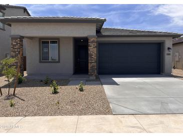 Charming single-story home featuring a two-car garage, desert landscaping, and a covered entryway at 23335 W Monona Ln, Surprise, AZ 85387