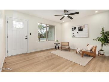 Bright living room featuring a ceiling fan, light hardwood floors, and a window with natural light at 252 S Cholla St, Gilbert, AZ 85233