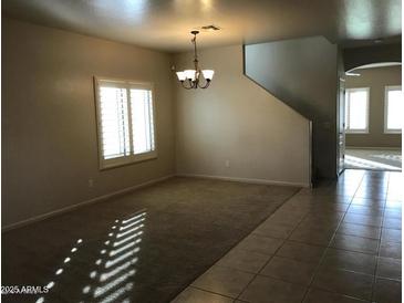 Neutral living room with large windows and plenty of natural light shining across tiled entryway at 42920 N Raleigh Ct, Anthem, AZ 85086