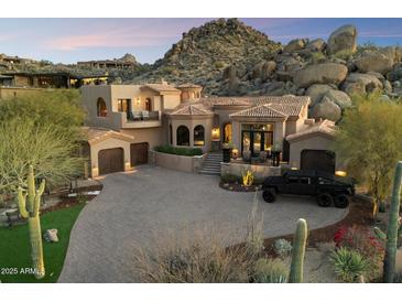 Luxurious Tuscan-style home with a circular driveway, grand staircase, and desert landscaping against a mountain backdrop at 10471 E White Feather Ln, Scottsdale, AZ 85262