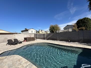 Beautiful backyard pool with hot tub, lounge chairs, and privacy fence for relaxing and entertaining outdoors at 19045 N 45Th Ave, Glendale, AZ 85308