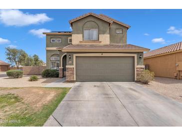 Two-story home with a two-car garage, stone accents, and a well-maintained front yard under a sunny sky at 6409 S 49Th Dr, Laveen, AZ 85339